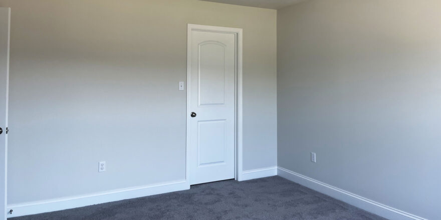 an empty room with a white closet door and carpet