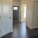 an empty room with white doors and hard wood floors
