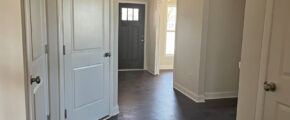 an empty room with white doors and hard wood floors