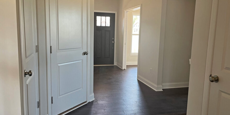 an empty room with white doors and hard wood floors