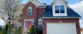 a brick house with two car garage and a pink door