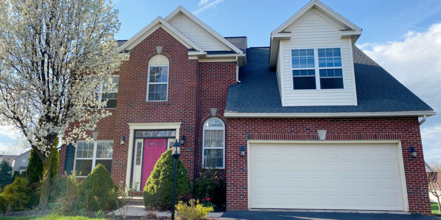 a brick house with two car garage and a pink door