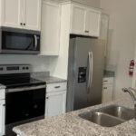 a kitchen with white cabinets and granite counter top