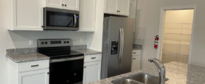 a kitchen with white cabinets and granite counter top