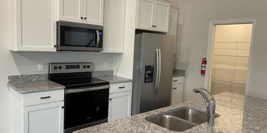 a kitchen with white cabinets and granite counter top