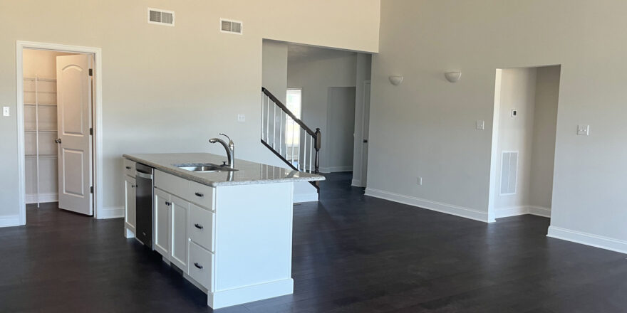 an empty kitchen and living room with hardwood floors