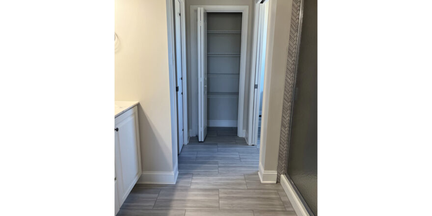 bathroom with vanity on left and shower on right and a view of closet directly ahead