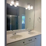 two sinks under a large mirror and vanity