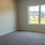 an empty room with a large window and carpet