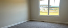 an empty room with a large window and carpet