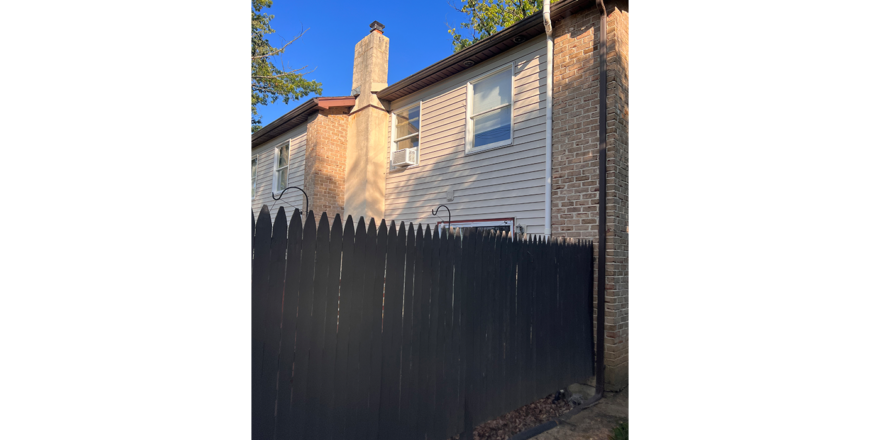 a house with a tall black fence in the back of it