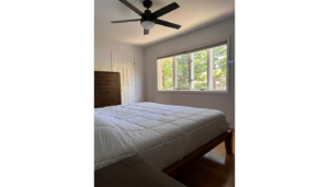 a bedroom with a bed, window, and ceiling fan