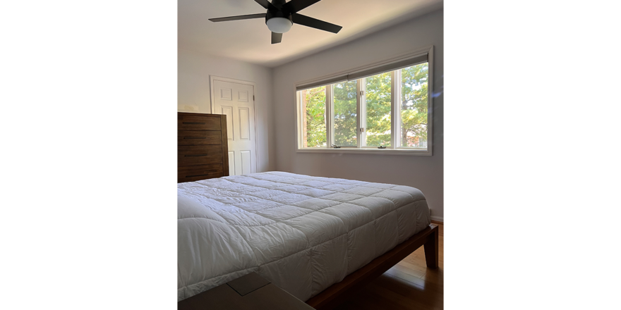 a bedroom with a bed, window, and ceiling fan