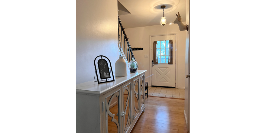 a hallway with a white cabinet and wooden floors