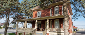 a red house with a porch next to a tree