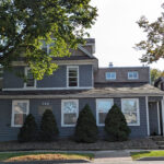 a gray house with trees in front of it