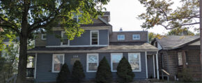 a gray house with trees in front of it
