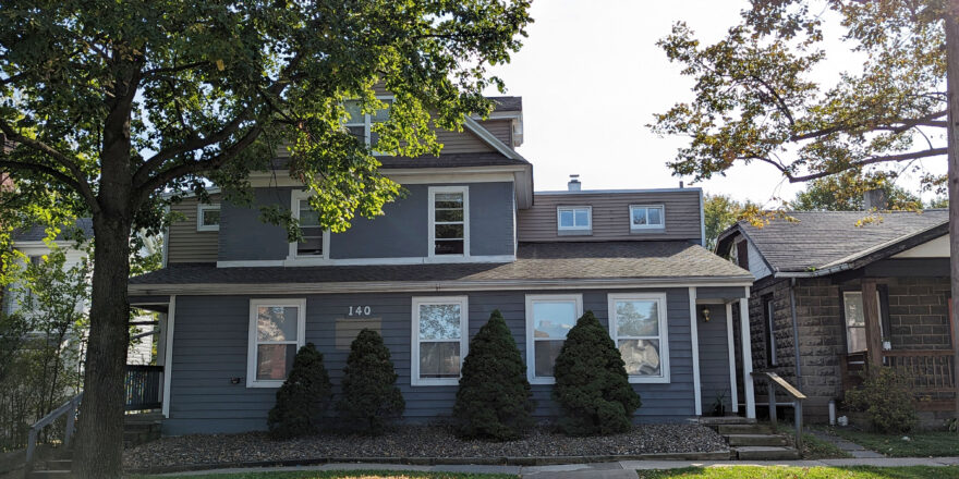 a gray house with trees in front of it