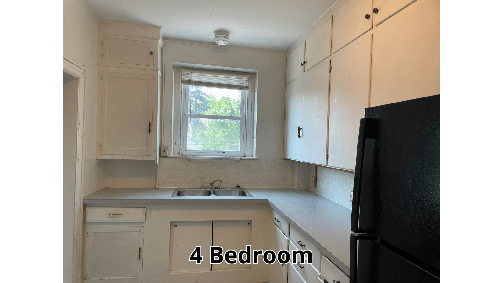 Kitchen with white cabinets and black refrigerator