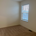 an empty room with a window and carpet