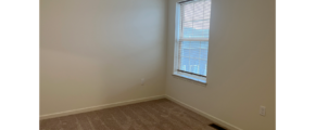 an empty room with a window and carpet