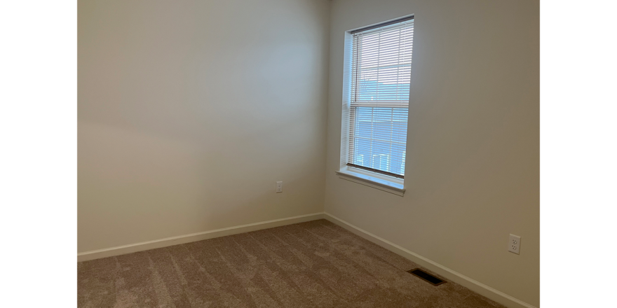 an empty room with a window and carpet