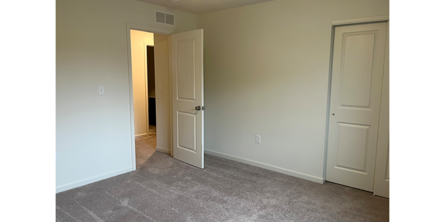 an empty room with two doors and carpet
