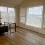 a living room with hard wood floors and large windows