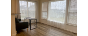 a living room with hard wood floors and large windows