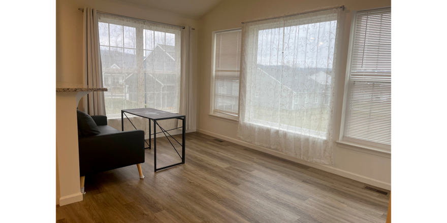 a living room with hard wood floors and large windows