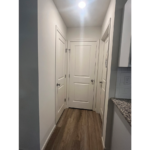 an empty hallway with white doors and wood floors