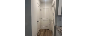 an empty hallway with white doors and wood floors