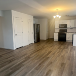 an empty kitchen with white cabinets and wood floors