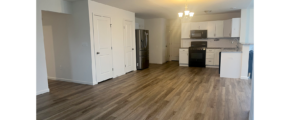 an empty kitchen with white cabinets and wood floors