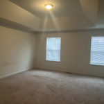 an empty room with two windows and carpet