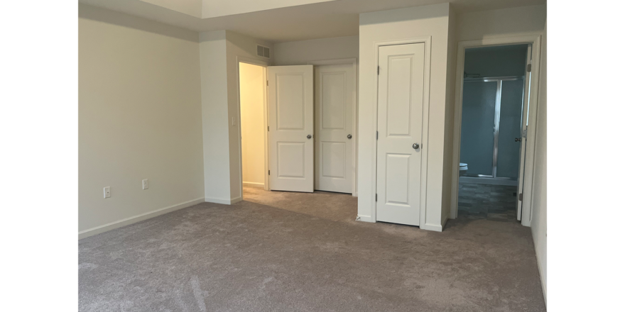 an empty room with white doors and carpet