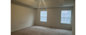 an empty room with two windows and carpet