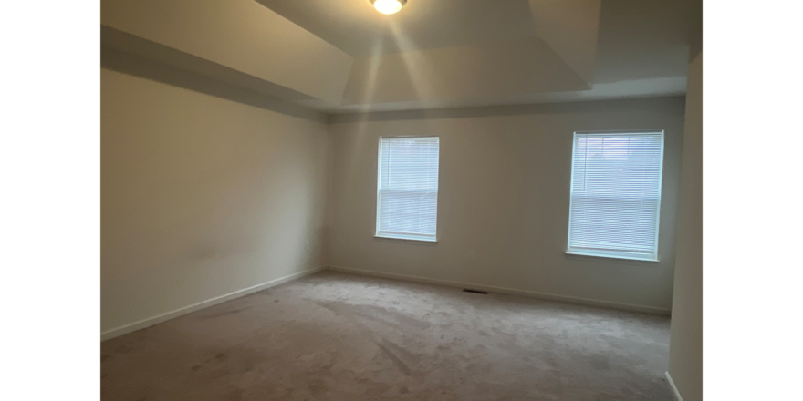 an empty room with two windows and carpet