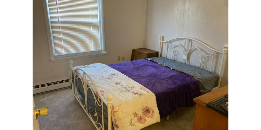 a bedroom with a bed, dresser and window