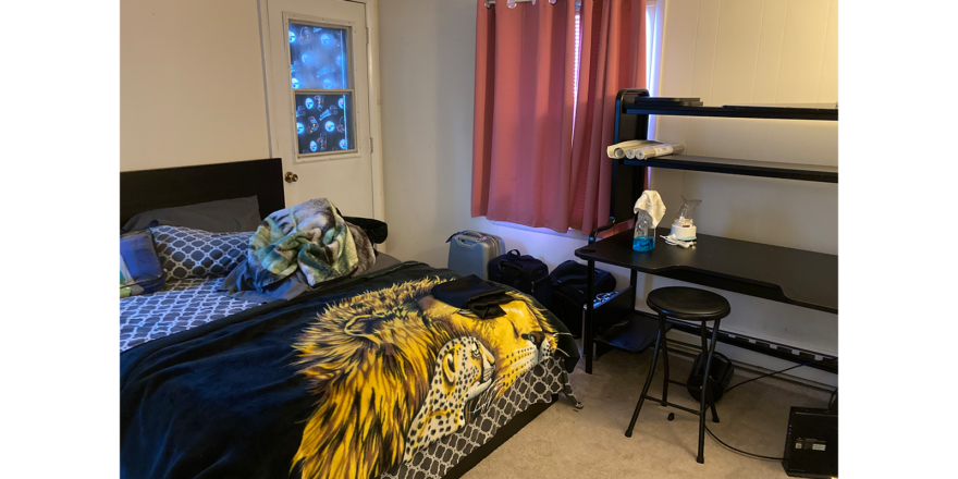 a bed room with a neatly made bed and a desk