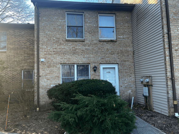 a brick building with a white door and three windows