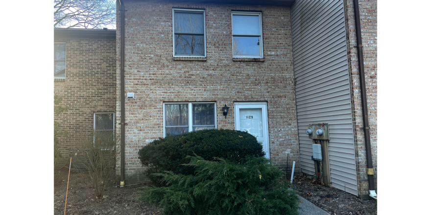 a brick building with a white door and three windows