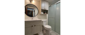 a white toilet sitting next to a walk in shower and sink with mirror