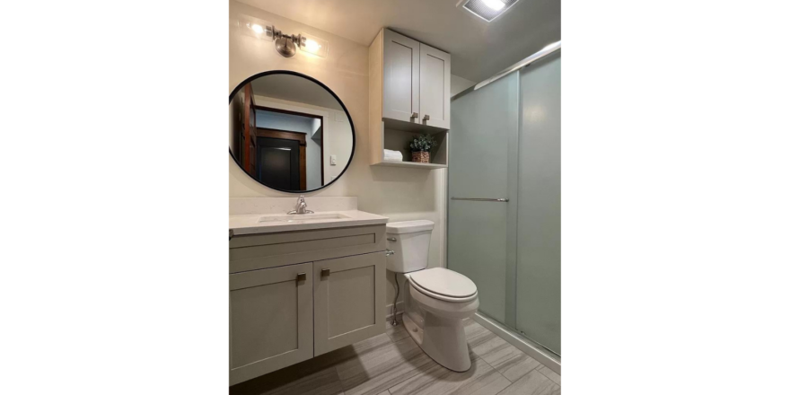 a white toilet sitting next to a walk in shower and sink with mirror
