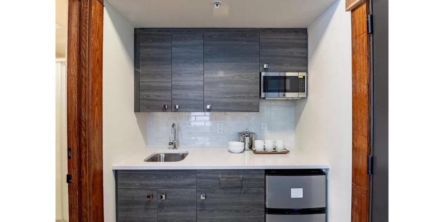 a kitchenette with a mini refrigerator, sink and microwave