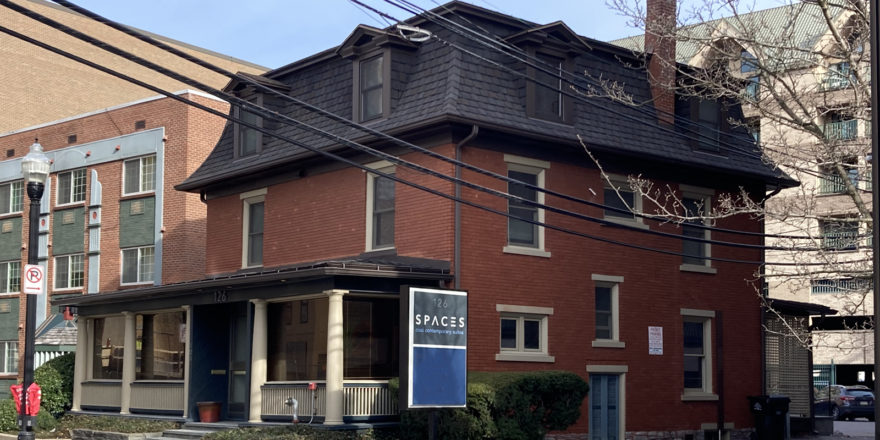 a red brick building with a black shingled roof on the corner of a street