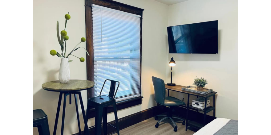 a room with a desk, chair and television