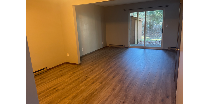 an empty living room with hard wood floors and sliding glass doors