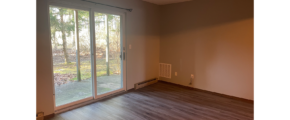 an empty living room with sliding glass doors and hard wood flooring