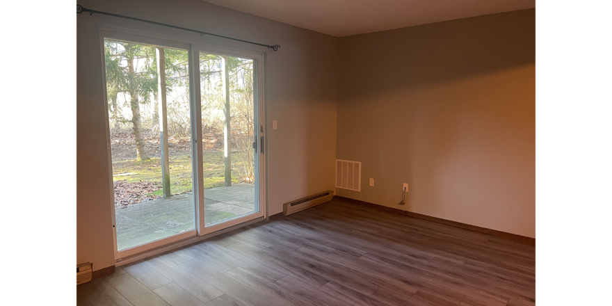 an empty living room with sliding glass doors and hard wood flooring